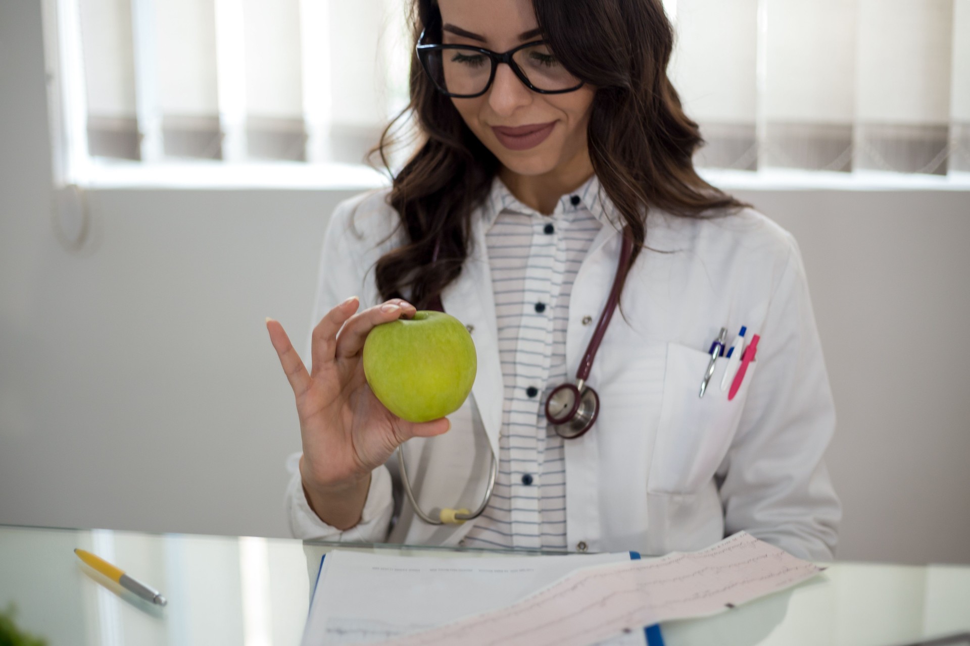 Medical doctor woman smile with stethoscope hold green fresh apple in hand.